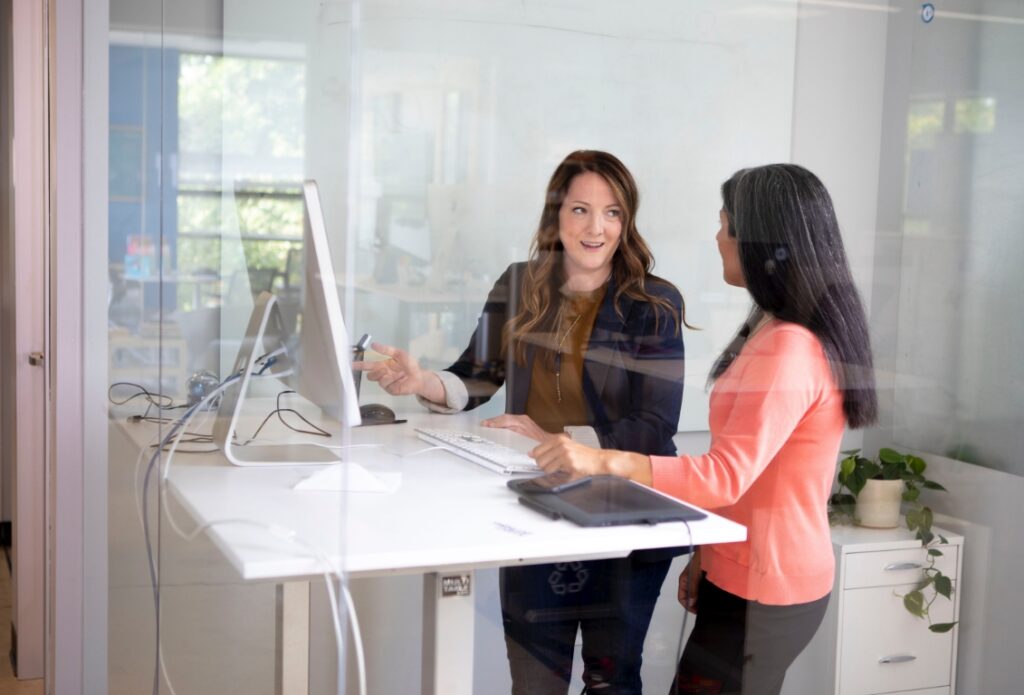 Two women standing near a computer