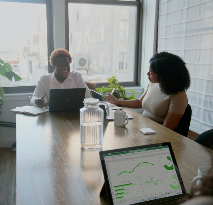 2 women sitting at a table with laptops