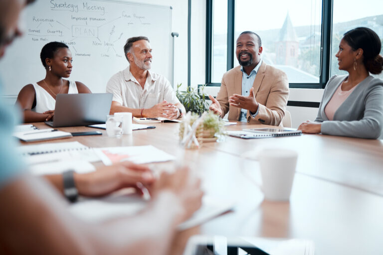 a group of employees around a table with a whiteboard in the background