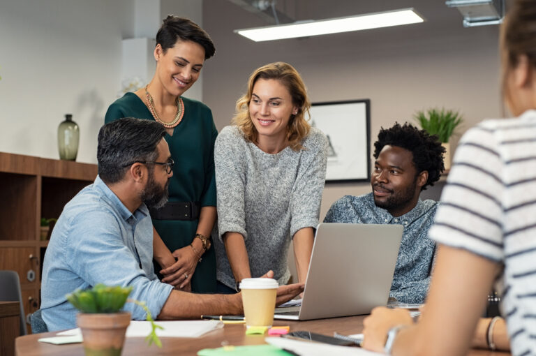 group of employees at a table looking at a laptop