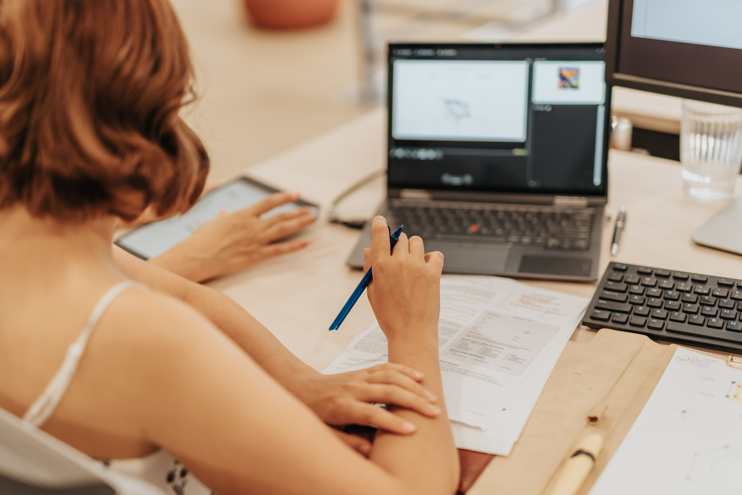 female employee holding a pen in front of a laptop and papers