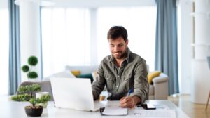 a person sitting at a table with a laptop and pen