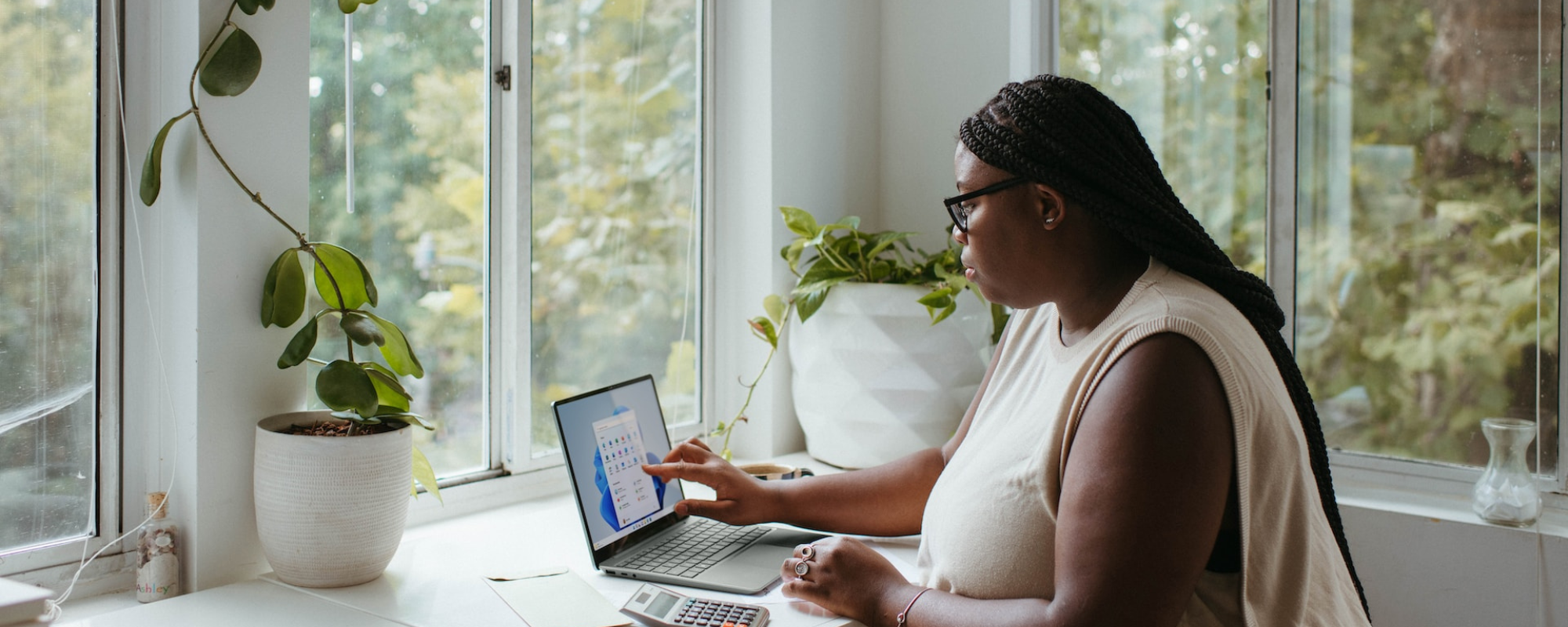 woman working from home on laptop with plants in background