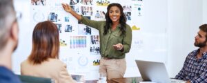 Woman points to board with charts, photos, and graphs