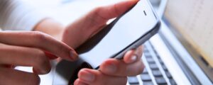 A closeup of a hand holding a cell phone and touching it with their finger