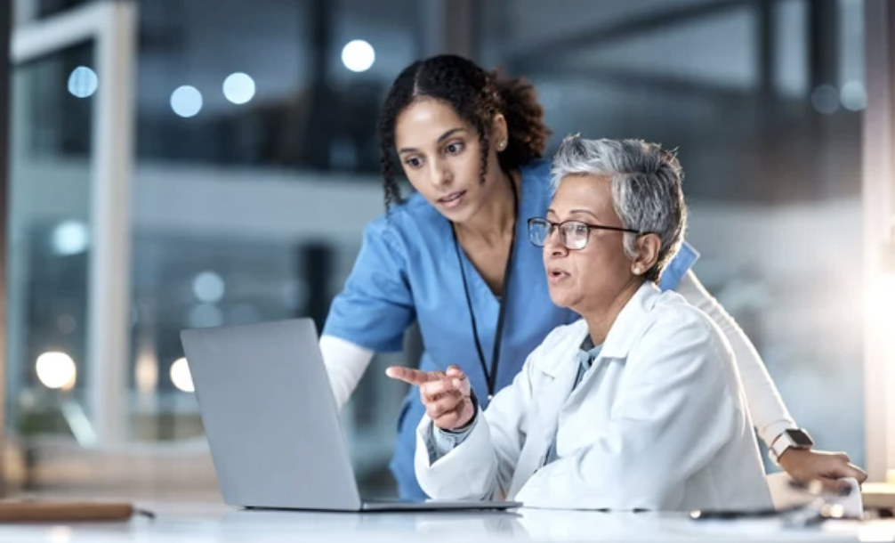 Two women medical professionals collaborating on a laptop