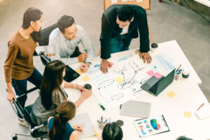 a group of people sitting around a table with a whiteboard