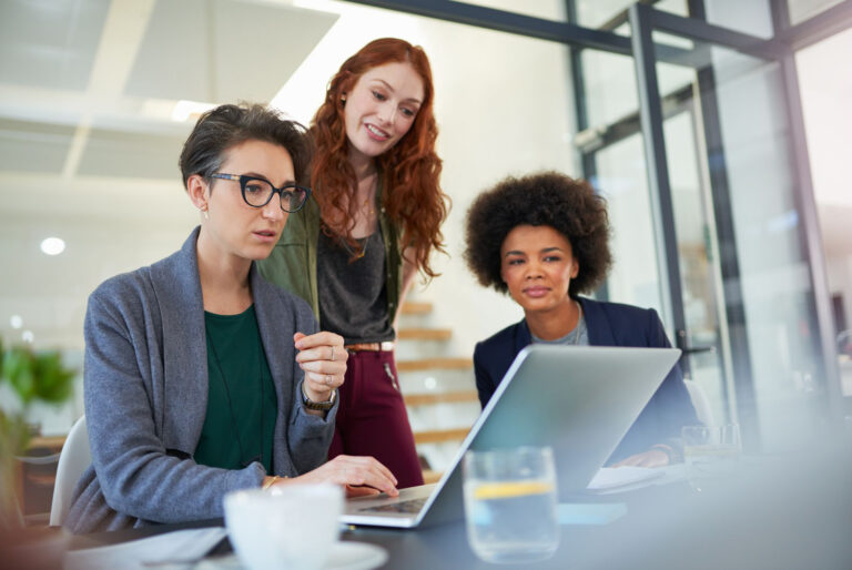 a group of women in an office evaluating automation tools on a laptop