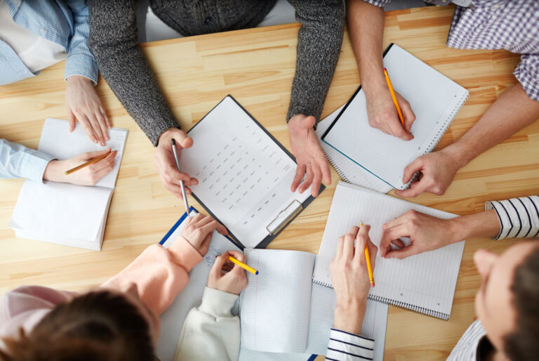 group of people sitting around a table writing their top lessons from 2024